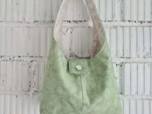 Green hobo bag hanging on the white brick wall